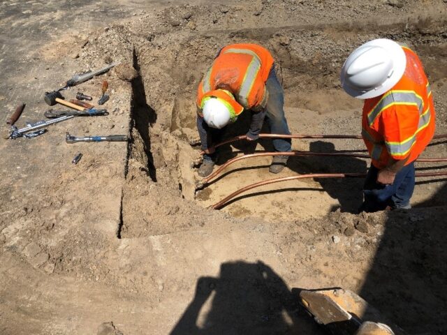 Workers installing pipe in a trench.